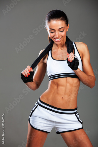A beautiful young sports girl on a gray background  beautiful abdominal muscles  a beautiful figure.