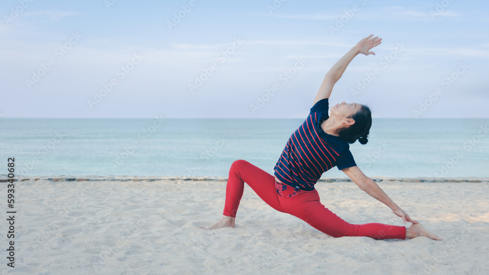 Strong Asian senior elder woman practicing yoga on the beach in summer morning with beautiful blue sky. Healthy lifestyle and fitness leisure concept. Strong Asian senior elder woman practicing yoga on the beach in summer morning with beautiful blue sky. Healthy lifestyle and fitness leisure concept.