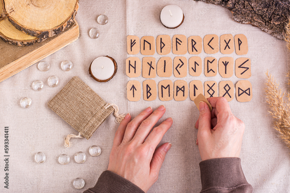 Female hands lay out homemade cardboard runes in rows on the table top ...