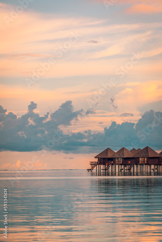 Amazing sunset panorama at Maldives. Luxury resort hotel villas seascape, calm sea water surface under colorful sky. Ocean lagoon, stunning romantic skyscape, seascape. Relax inspire vacation beach