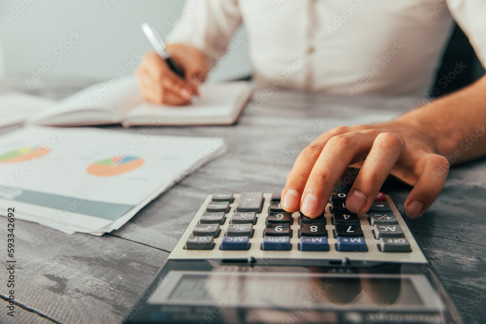 A man writes in a notebook and counts in front of statistics A man writes in a notebook and counts in front of statistics