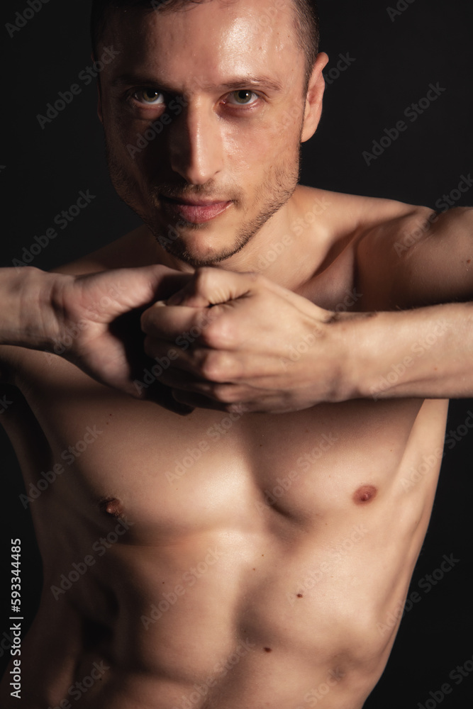 Fototapeta premium Adult attractive man with a beautiful body posing in the studio. Black background.