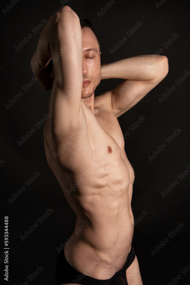 Adult attractive man with a beautiful body posing in the studio. Black background. Adult attractive man with a beautiful body posing in the studio. Black background.