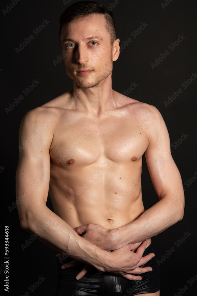 Naklejka premium Adult attractive man with a beautiful body posing in the studio. Black background. 