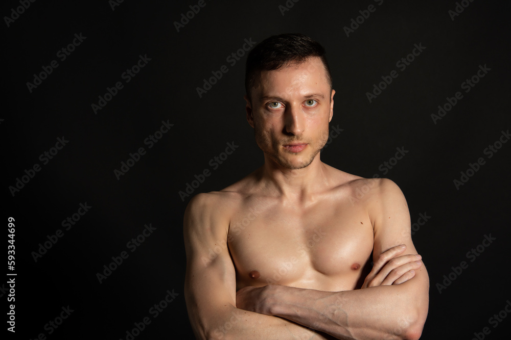 Adult attractive man with a beautiful body posing in the studio. Black background. Adult attractive man with a beautiful body posing in the studio. Black background.