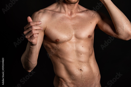 Adult attractive man with a beautiful body posing in the studio. Black background. 