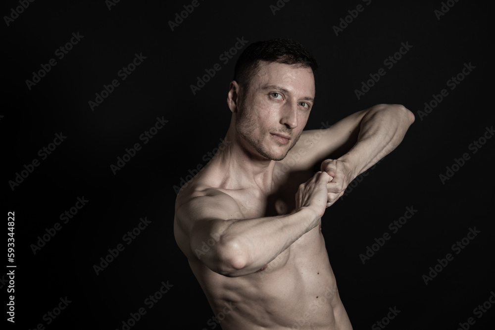 Adult attractive man with a beautiful body posing in the studio. Black background.	