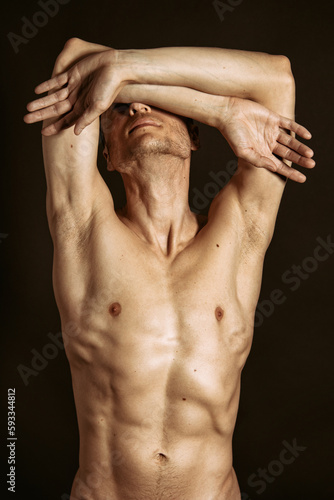 Adult attractive man with a beautiful body posing in the studio. Black background. 