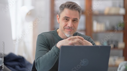 50s businessman with gray hair working from home. Man in casual sitting at desk using laptop computer, business manager online in home office.