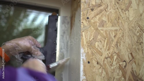 Hand with brush carefully paints slopes of windows of his own wooden house