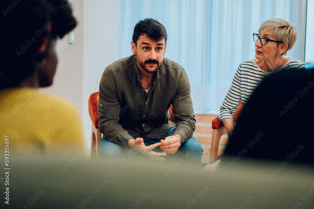 Young man talking about his mental health on a group therapy session ...