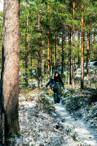 Female hiker in winter forest. woman walking on trail in snowy forest, Active rural travel and adventure concept