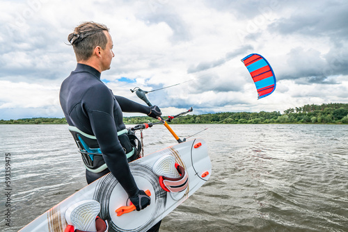 Photography Kitesurfer with board and kite in air before start on lake