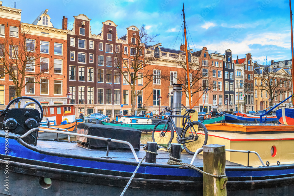 Cityscape on a sunny winter day - view of the houseboats on the water canal in the historic center of Amsterdam, the Netherlands