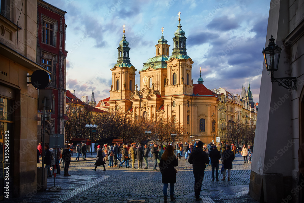 Obraz premium Prague, Czech Republic. View at the Saint Nicholas Church Staromestska square in centre of Prague Old Town. Evening sunset and people walking by street