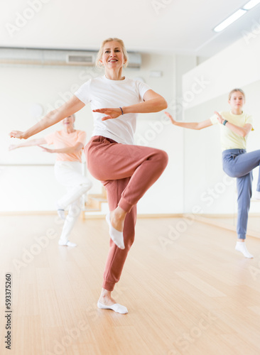 Caucasian woman learning aerobic dance during group training in studio.