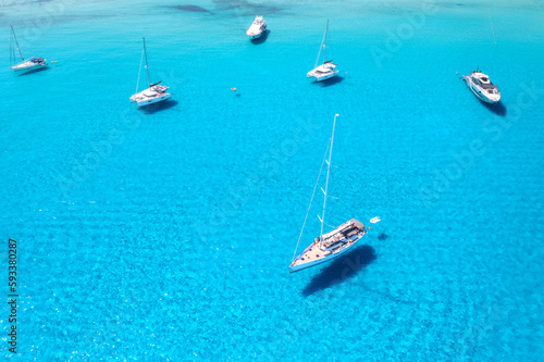 Aerial view of beautiful luxury yacht and sailboats in blue sea at sunset in summer. Sardinia island, Italy. Top view of speed boat, sea coast, transparent water. Travel. Tropical landscape. Yachting  © den-belitsky