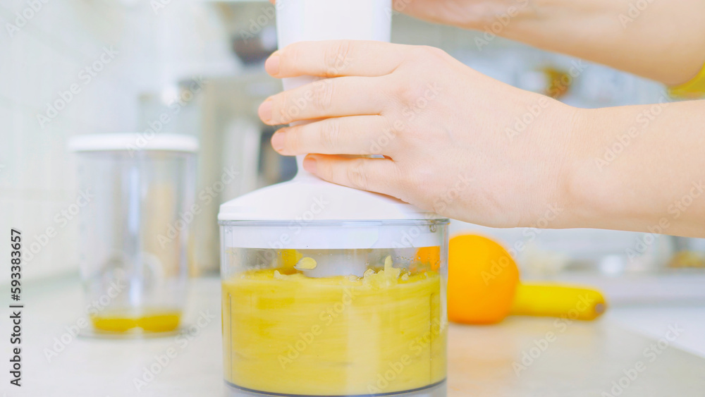 In a kitchen, a young woman prepares a healthy smoothie using a blender. Surrounding her are fresh fruits, including sliced pineapple on a wooden cutting board. nutrition and healthy eating.