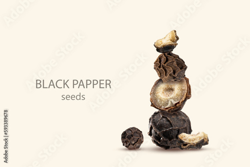 Close-up of a stack of Organic dried black pepper seeds, whole and sliced peppercorn on a beige background.Tower of picy Seasoning. Equilibrium floating food balance. Creative concept. Copy space photo