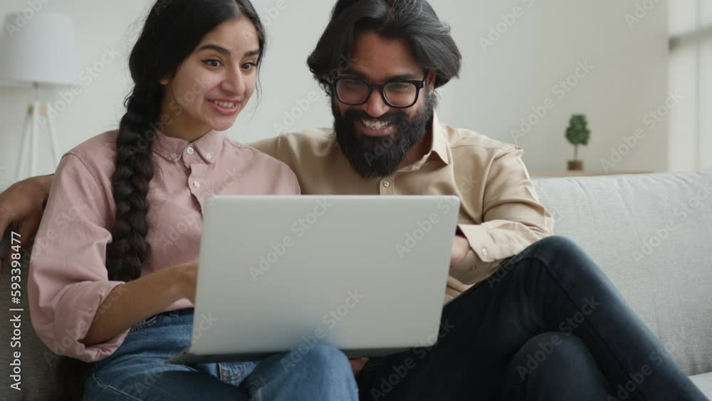 Excited happy couple read email on laptop at home celebrate amazing news give high five bet win victory receive loan credit Indian Arabian ethnic woman man celebrate online success mortgage approval Excited happy couple read email on laptop at home celebrate amazing news give high five bet win victory receive loan credit Indian Arabian ethnic woman man celebrate online success mortgage approval