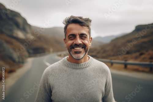 Portrait of a handsome middle-aged man with a beard and mustache in a gray sweater on a mountain road. © Robert MEYNER