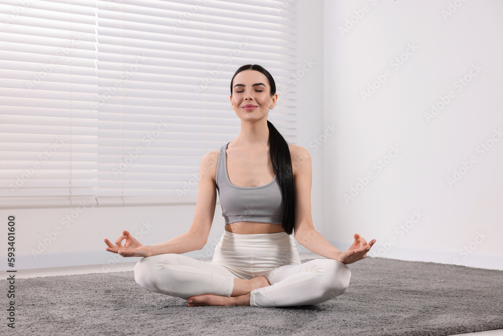 Woman in sportswear meditating indoors. Harmony and zen