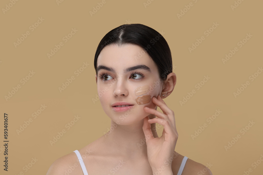 Teenage girl with swatches of foundation on face against beige background Teenage girl with swatches of foundation on face against beige background