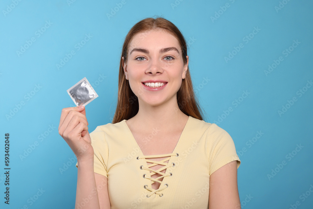 Woman holding condom on turquoise background. Safe sex Woman holding condom on turquoise background. Safe sex