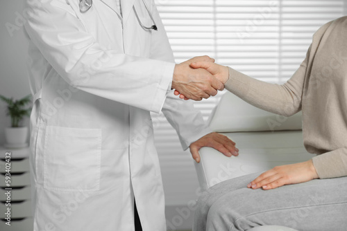 Senior doctor shaking hands with patient in clinic, closeup
