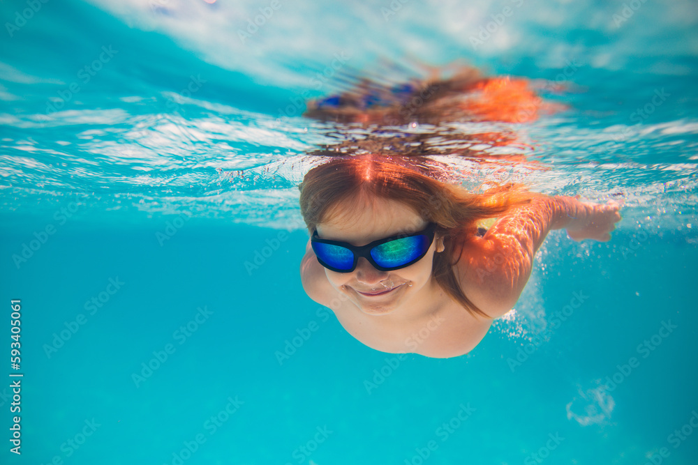 Child dives into the water in swimming pool. little kid swim underwater in pool. Child swimming underwater in sea or pool water. Summer vacation fun. Underwater portrait cute kid in swimming pool.