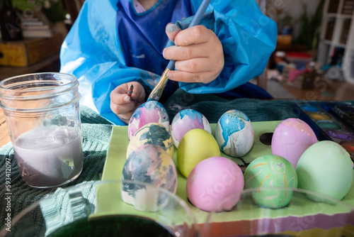 2 year old paints Easter eggs with watercolor and craft paint; fine motor skill development