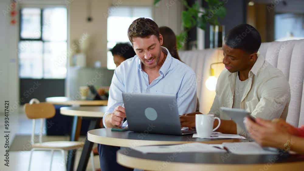 Two businessmen working on laptop in informal seating area of modern office on coffee break - shot in slow motion Two businessmen working on laptop in informal seating area of modern office on coffee break - shot in slow motion