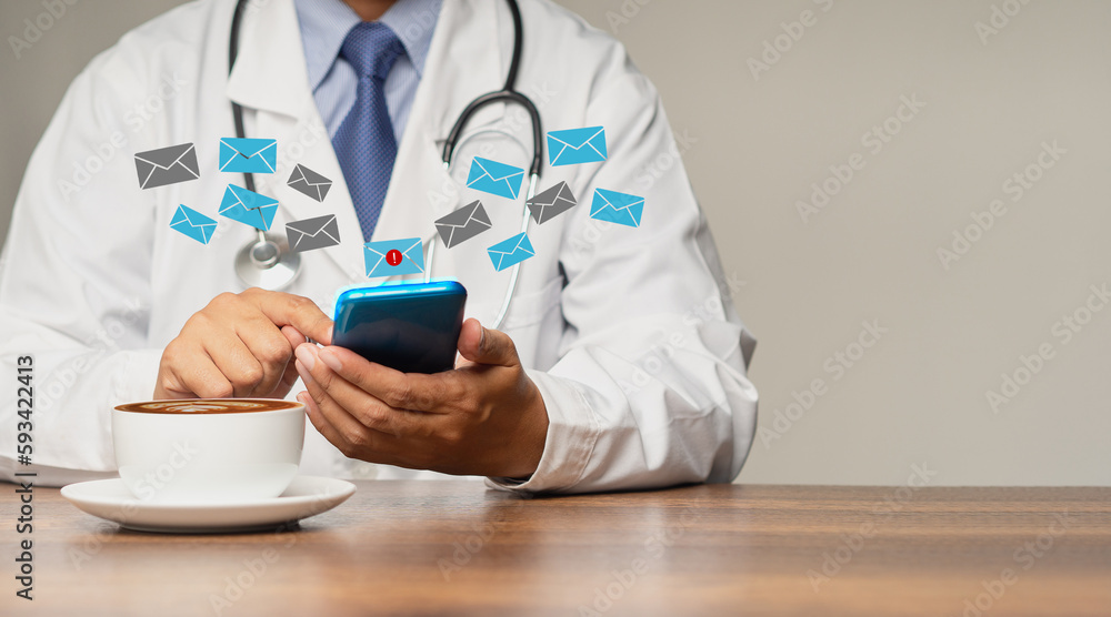 Doctor in uniform checks email on his smartphone while sitting in the hospital Doctor in uniform checks email on his smartphone while sitting in the hospital