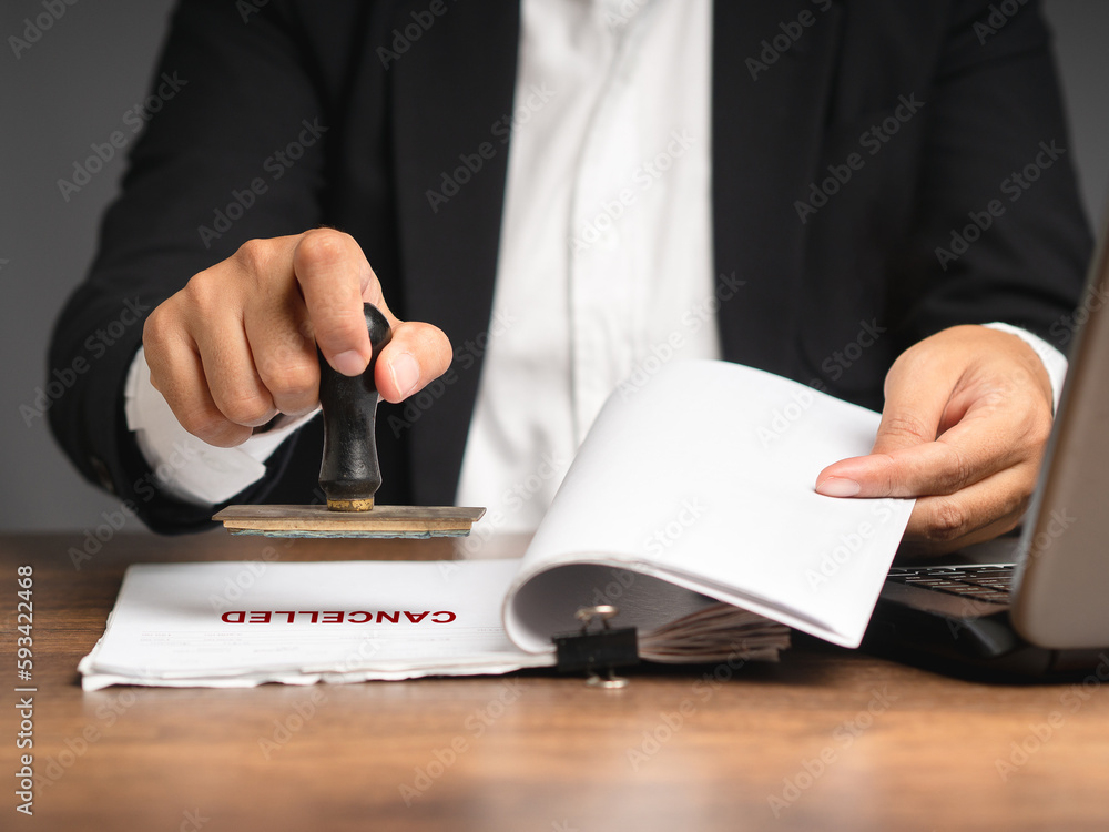 Businessman stamped for cancelled on a document while sitting in the office - obrazy, fototapety, plakaty 