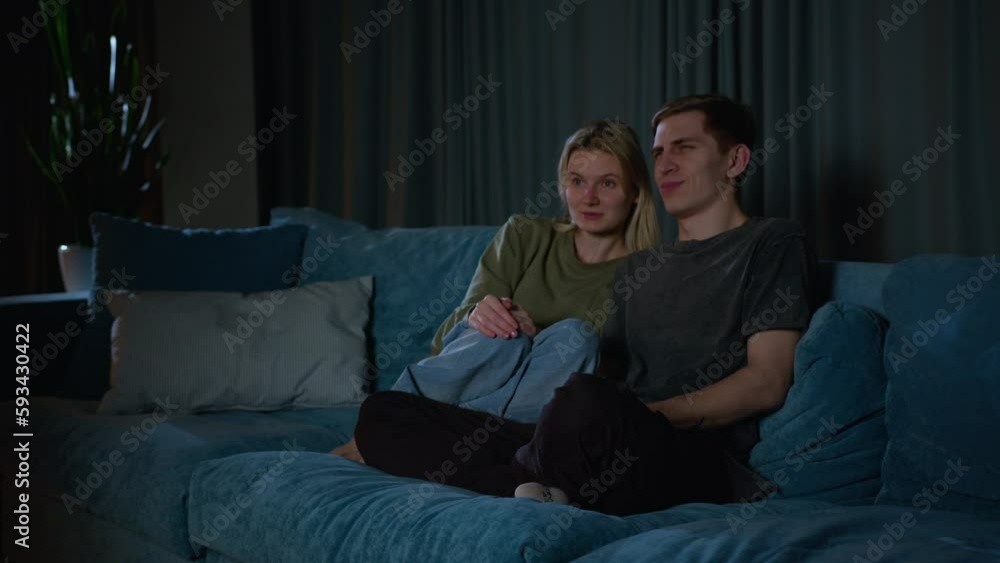beautiful young couple watching tv together. couple watching TV together and displaying emotional reactions. enjoying their time together, after a long day. sense of relaxation and companionship. beautiful young couple watching tv together. couple watching TV together and displaying emotional reactions. enjoying their time together, after a long day. sense of relaxation and companionship.