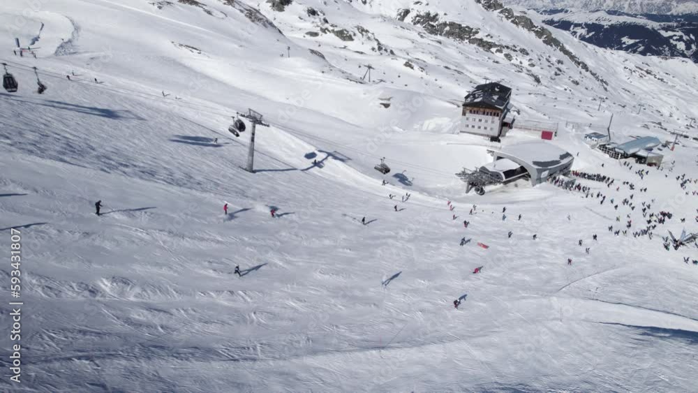 Aerial birds eye shot showing group of skier skiing down white snow-capped slope of mountain Aerial birds eye shot showing group of skier skiing down white snow-capped slope of mountain