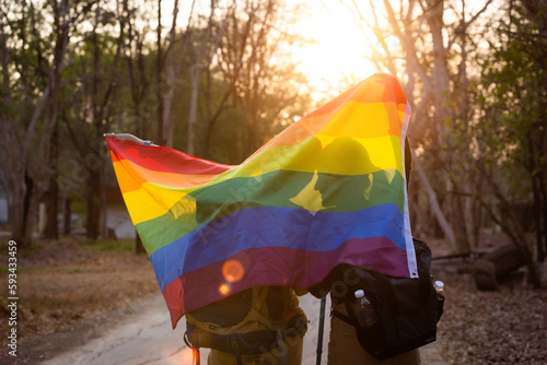 Lesbian couple hugging outdoors. LGBT rainbow flag.