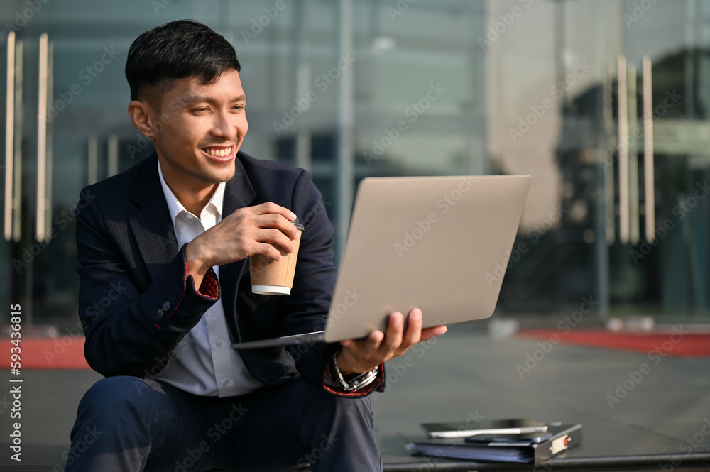 Professional Asian businessman checking his project on laptop while sitting on the stairs in a city. Professional Asian businessman checking his project on laptop while sitting on the stairs in a city.