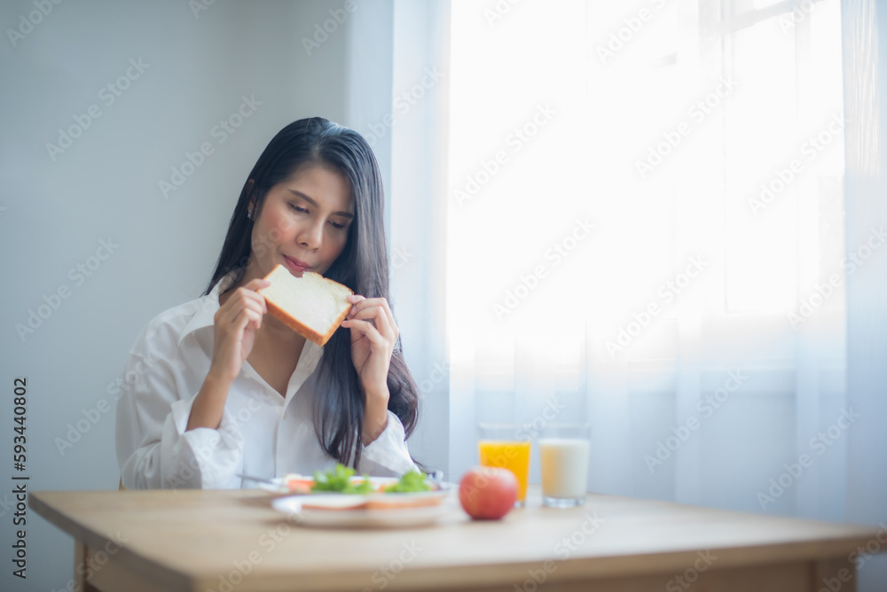 Beautiful asian woman savored the taste of the freshly baked bread on her breakfast table. Beautiful asian woman savored the taste of the freshly baked bread on her breakfast table.