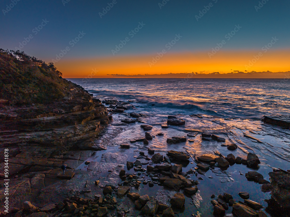 Sunrise over the sea and rocky Inlet with clear skies and a low cloudbank