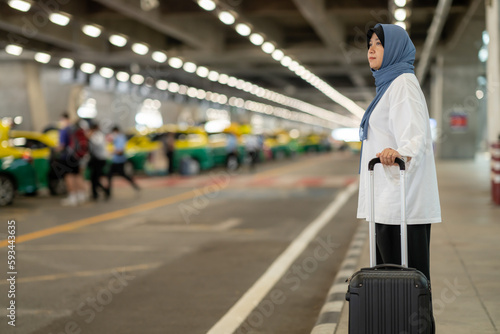 An Asian Muslim wearing a blue hijab is preparing for a vacation and she is at the airport. She's going to call a taxi, Muslim travelers.