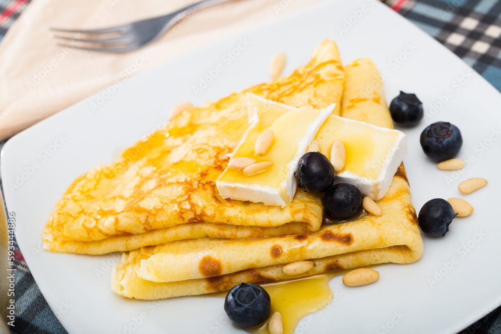Delicious tasty homemade crepes served with soft cheese and honey