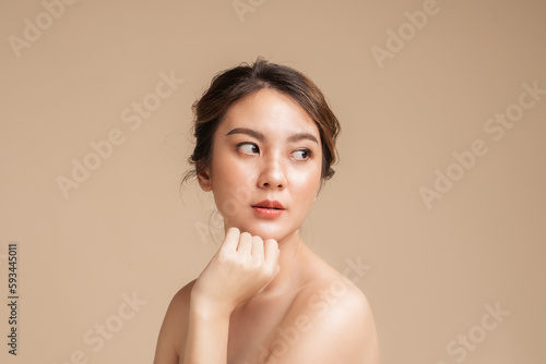 Beautiful asian woman in natural look makeup and showing perfect skin on isolated beige background.