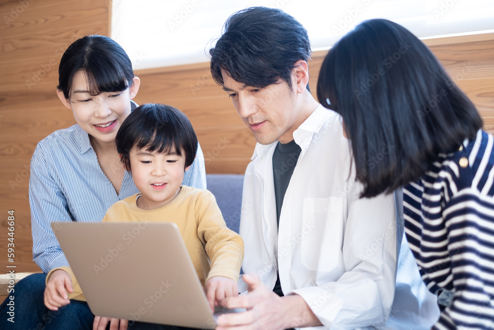 パソコンを触る男の子と見守る家族 パソコンを触る男の子と見守る家族