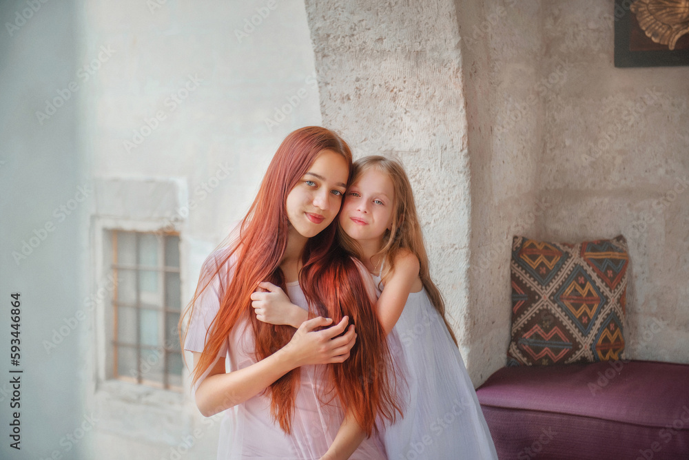 Fototapeta premium Beautiful girls. Mom and daughter. Sisters on vacation. Rest at the hotel. Holidays. Beautiful sisters with long hair. The sisters hug. Vacation. Relax. Cappadocia. Two sisters. Tenderness. Family. 