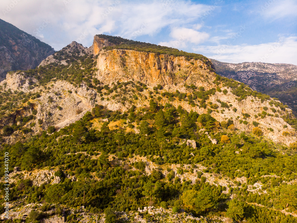 Scenic view of crag with rock hewn tombs towering over ancient Lycian city of Pinara, Mugla Province, Turkey