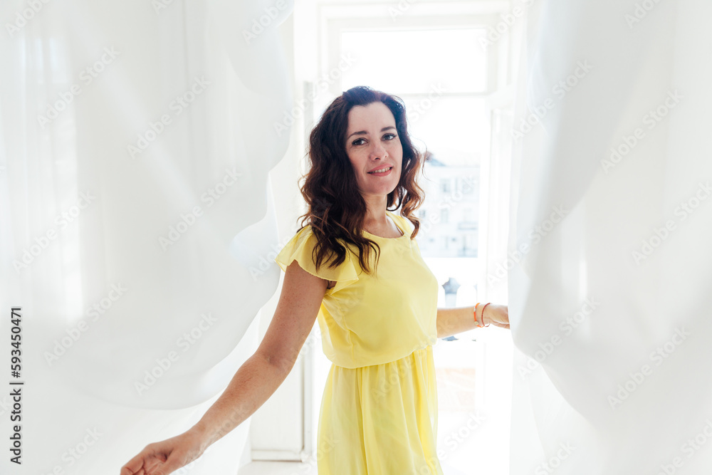 beautiful brunette woman in yellow dress standing in white fabrics beautiful brunette woman in yellow dress standing in white fabrics