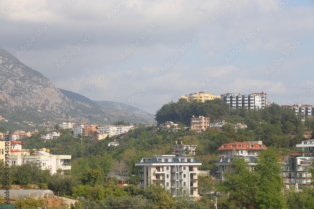 View of the highway, houses and mountains in Alanya, orange groves. Evening time, Türkiye, April 2023.