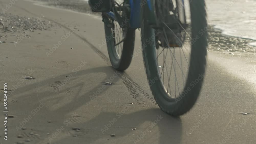 cyclist rides leaving tyre prints on wet sand, near sea coast, during early morning cyclist rides leaving tyre prints on wet sand, near sea coast, during early morning