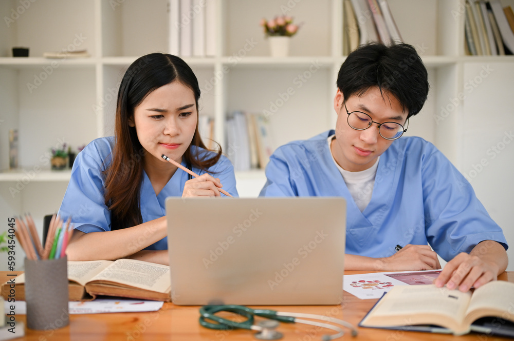 Focused Asian medical students are researching medical information and studying together Focused Asian medical students are researching medical information and studying together